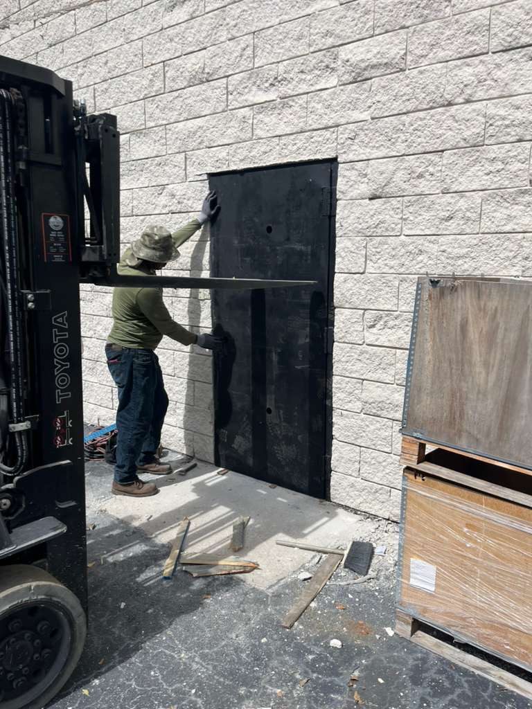 Fine Edge Industries moving a fabricated steel door into place with a forklift at a Doral facility